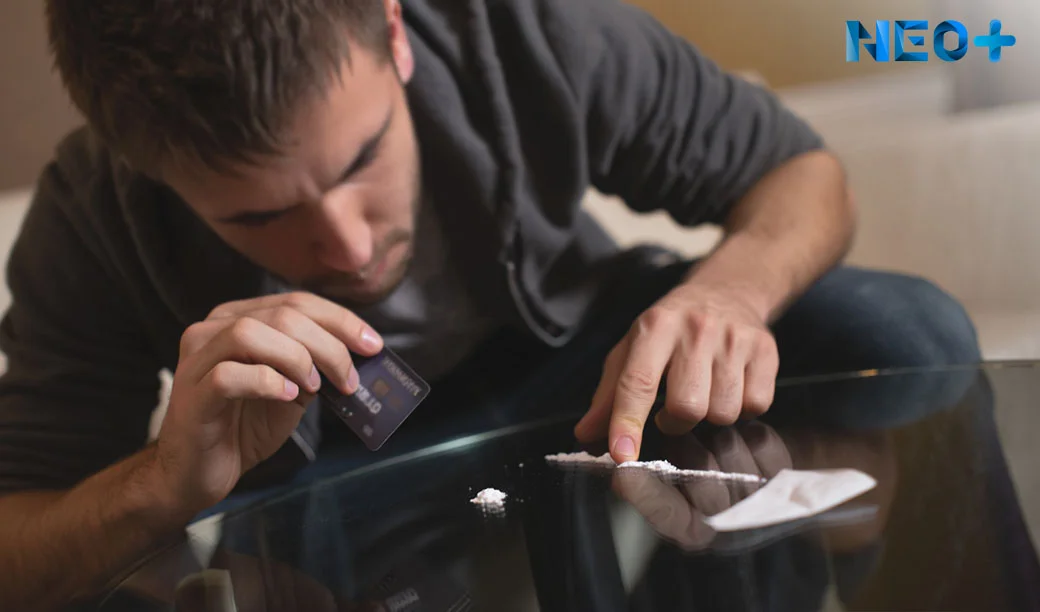 Мужчина наклонился перед столом с белым порошком